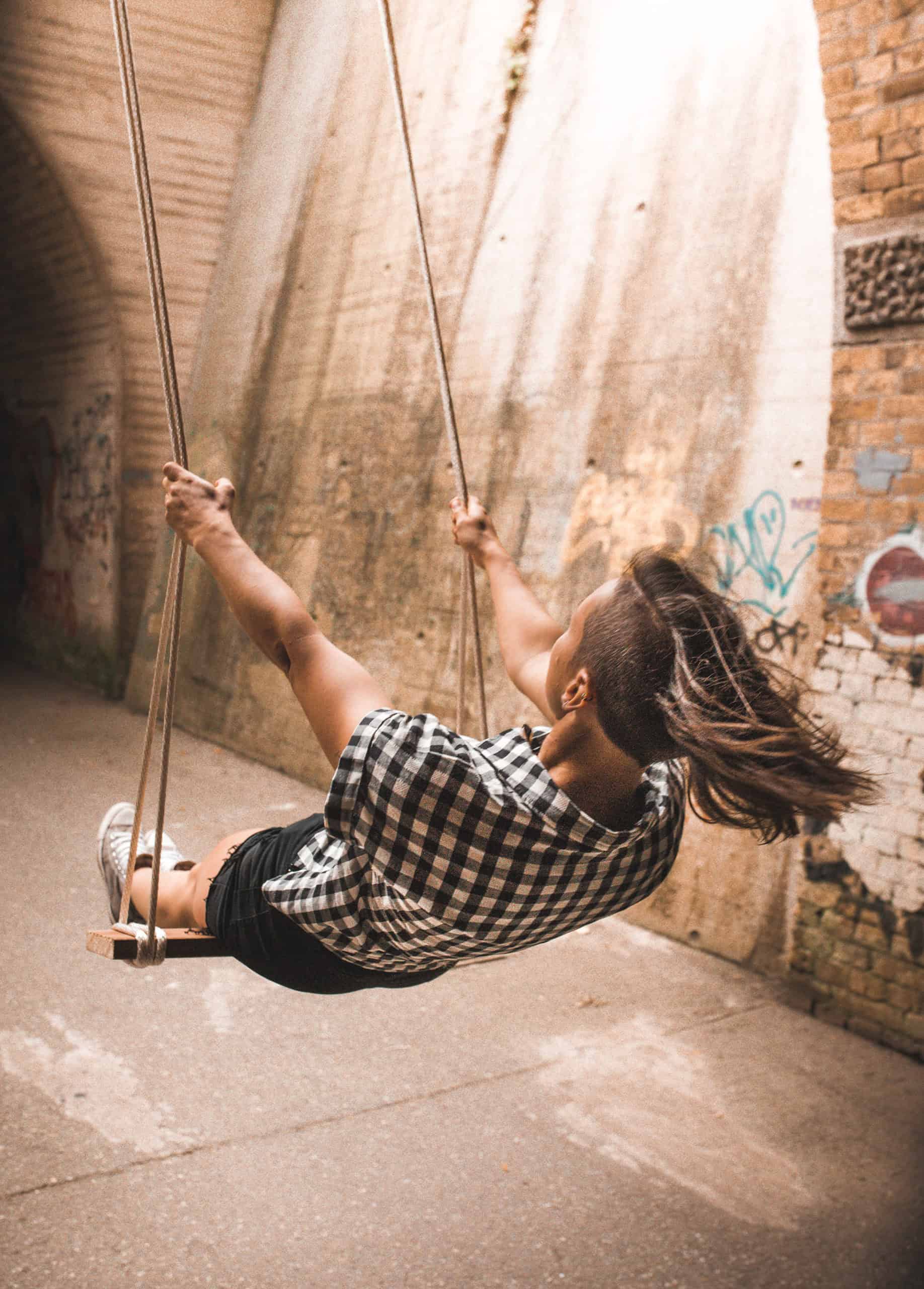 Rückansicht einer Frau, die auf der Schaukel Schwung holt