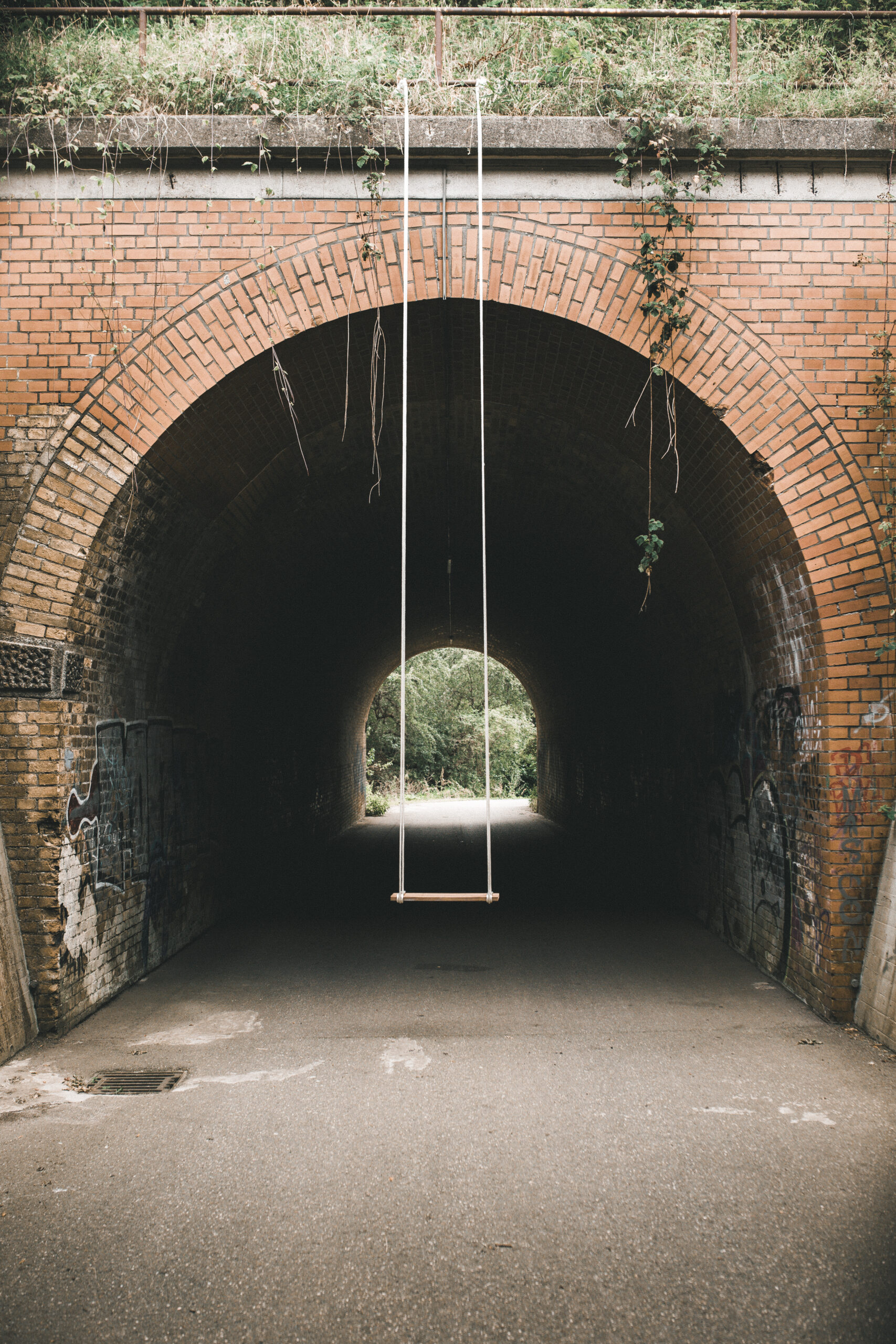 Frontalansicht eines Tunnel-Rundbogens, an dem eine mittig eine Schaukel hängt.