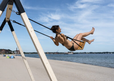 Pop-up Schaukel am Strand mit schaukelnden Frau im Bikini